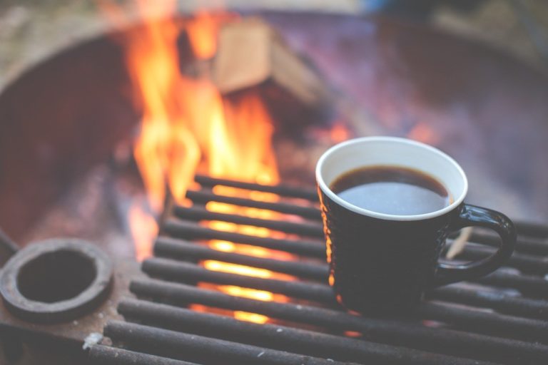 Fire in firepit with cup of coffee above